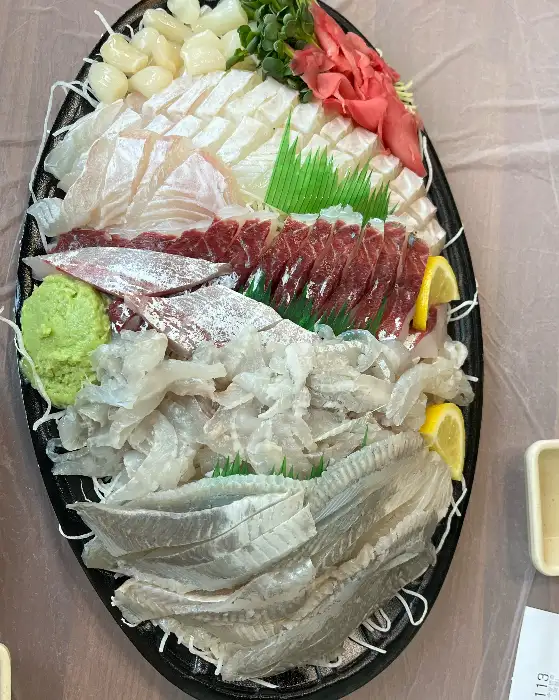 회 접시의 클로즈업 사진, 흰살 생선, 붉은 살 생선, 연어 등 다양한 회의 질감이 생생하게 보이는 모습