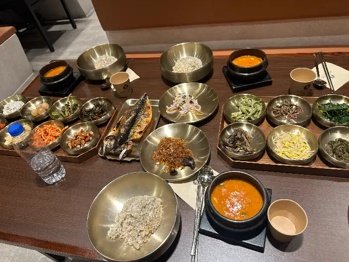 테이블 위에 차려진 보리밥과 반찬, 찌개 등의 다양한 음식 사진