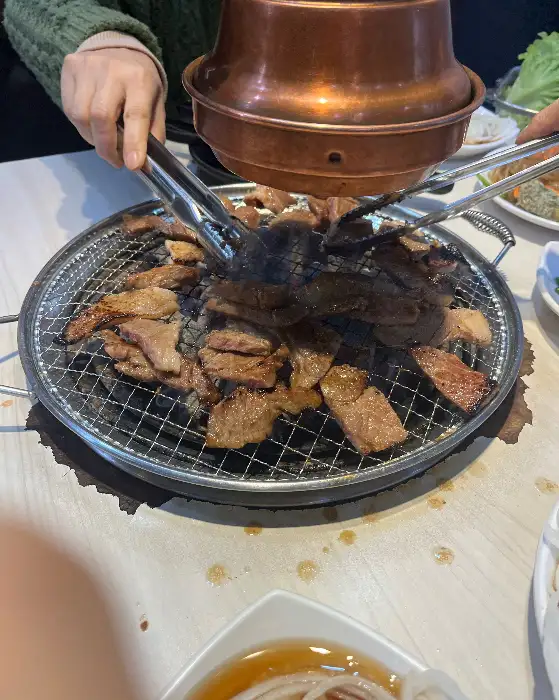 집게로 돼지갈비를 불판 위로 옮기는 모습