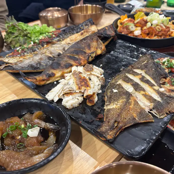 다양한 생선구이와 떡볶이, 샐러드가 담긴 식탁