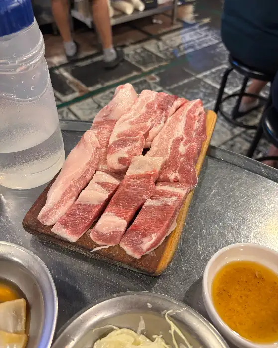 다양한 부위의 돼지고기 모듬이 나무 도마 위에 놓여 있습니다.