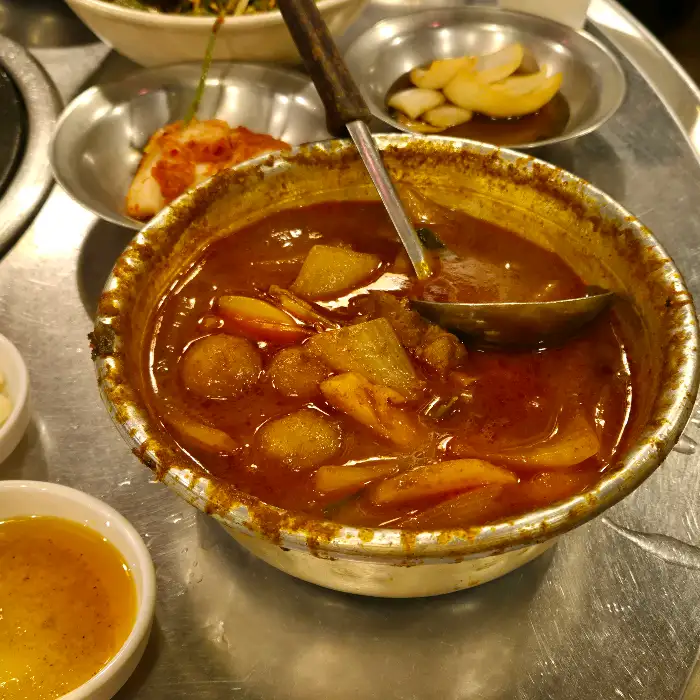 칼칼해 보이는 된장찌개가 놋그릇에 담겨 있습니다.