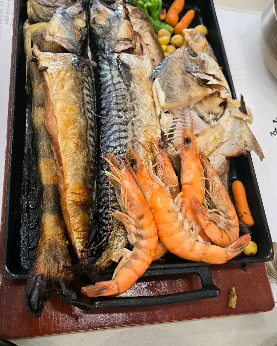 다양한 종류의 생선구이와 새우, 야채들이 담긴 철판