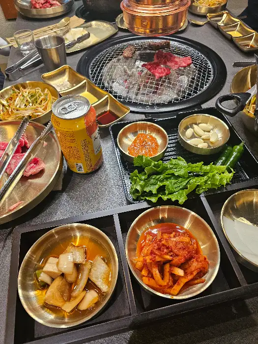 테이블 위에 차려진 다양한 반찬과 고기, 음료수