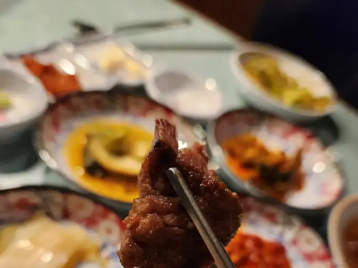 집게로 집어 올린 먹음직스러운 고기 한 점