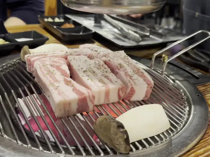숯불 위에서 정렬된 숙성 삼겹살과 버섯