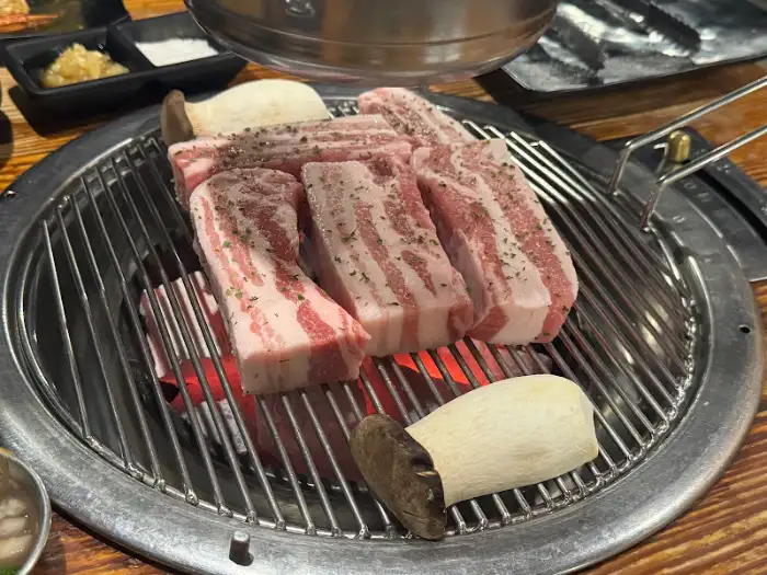 숯불 위에서 맛있게 익어가는 두툼한 숙성 삼겹살