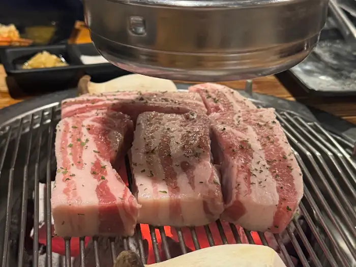 숯불 위에서 노릇하게 익어가는 삼겹살 조각들