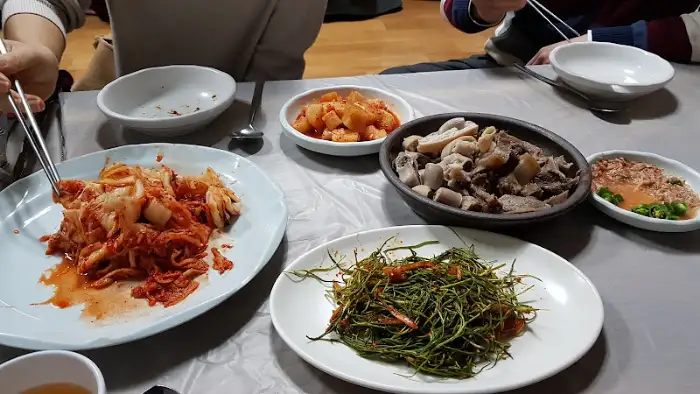 여러 음식이 놓인 식탁의 모습. 수육과 함께 김치, 채소 무침 등이 보인다.