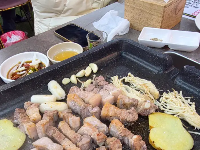 불판 위에서 구워지고 있는 삼겹살과 곁들임 재료들