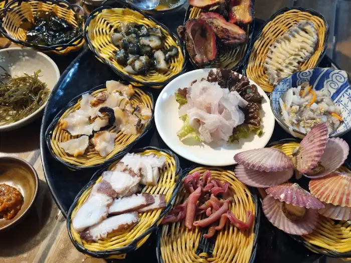 다양한 해산물 접시들이 테이블에 놓여 있고, 배경에는 바다가 보이는 풍경