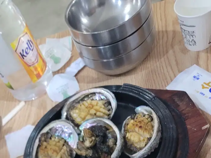 테이블 위에 놓인 전복 요리와 음료, 그리고 물잔