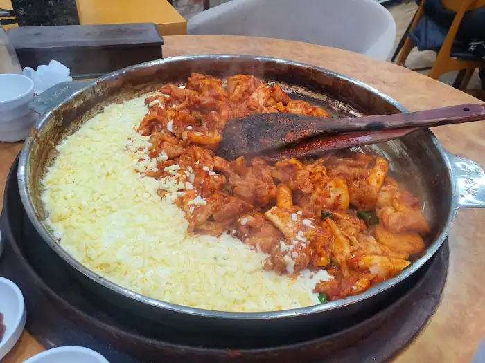 치즈가 덮인 닭갈비와 밥이 함께 조리되고 있는 모습
