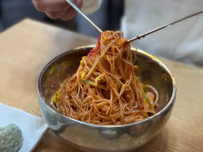 젓가락으로 비빔국수를 집어 올리는 모습