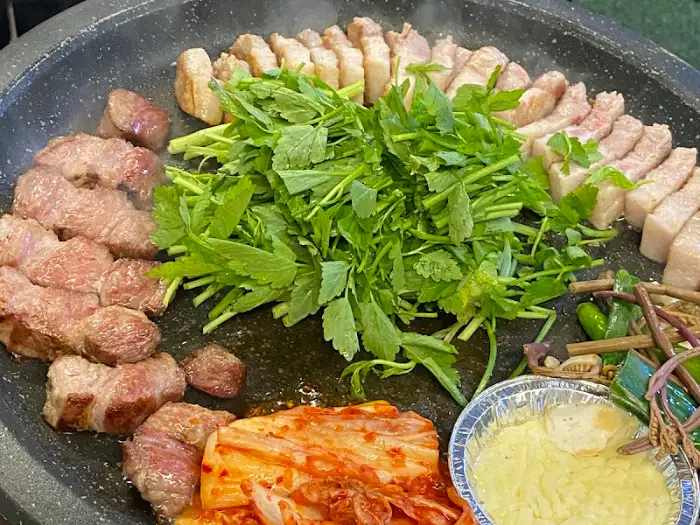 두툼한 삼겹살과 푸른 채소가 함께 구워지는 모습