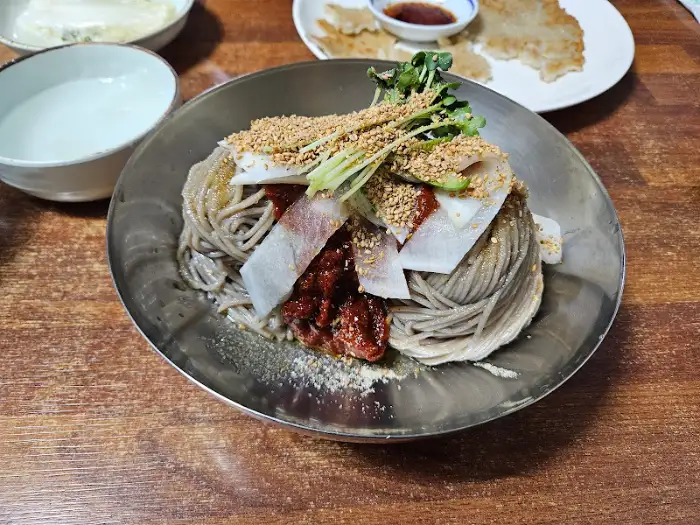 곱게 쌓인 메밀면 위에 양념과 고명이 얹어진 막국수