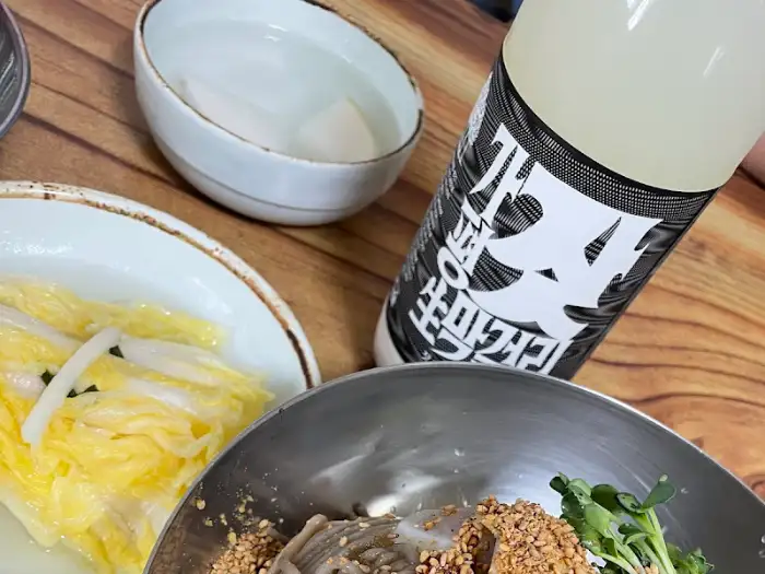 막국수 그릇 옆에 놓인 술병과 백김치