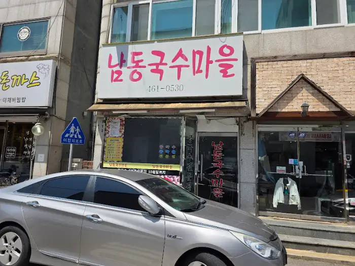 남동국수마을 가게 외부 전경. 하얀색 간판에 붉은 글씨로 상호명이 쓰여있고, 그 아래로 유리창 너머로 가게 내부가 보인다.