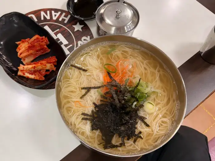 넓은 놋그릇에 담긴 잔치국수. 얇고 하얀 소면에 김가루, 채 썬 당근, 파가 고명으로 올라가 있고, 맑은 육수가 넉넉하다.