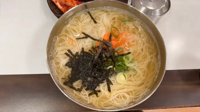 잔치국수 그릇의 위에서 본 모습. 얇은 소면과 김가루, 파, 당근 고명이 잘 어우러져 있다.
