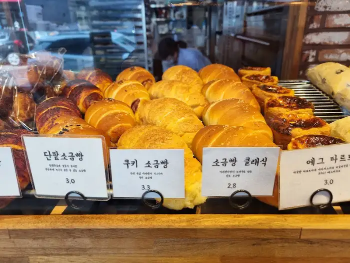 진열대 앞에 놓인 다양한 빵 이름과 가격표
