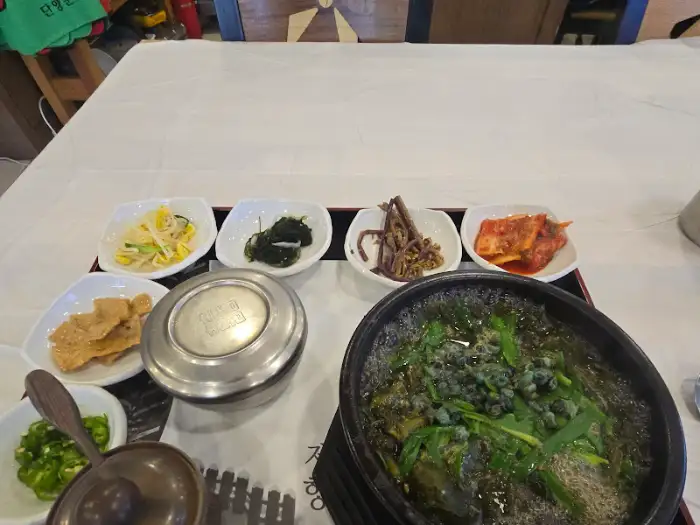 올갱이 해장국, 밥, 그리고 여러 밑반찬이 식탁에 놓여 있다.