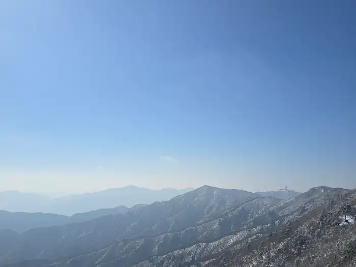 안개 낀 산봉우리들의 풍경. 푸른 하늘과 조화를 이룬다.