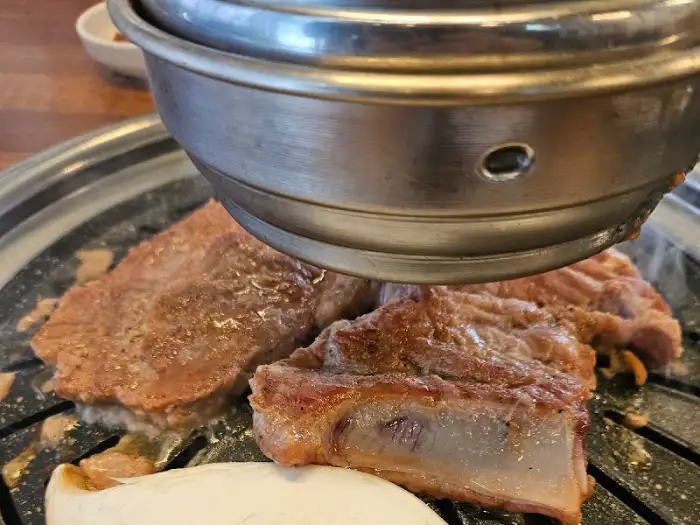 불판 위에서 익어가는 고기와 뚜껑