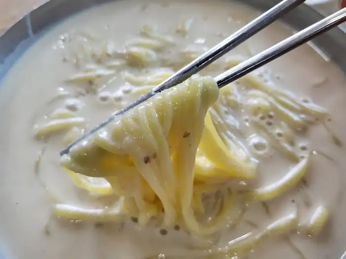 젓가락으로 콩국수 면발을 들어 올리는 모습