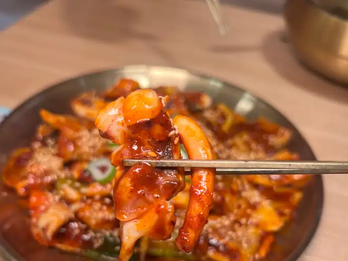 집게로 집어 올린 오징어 볶음 한 조각