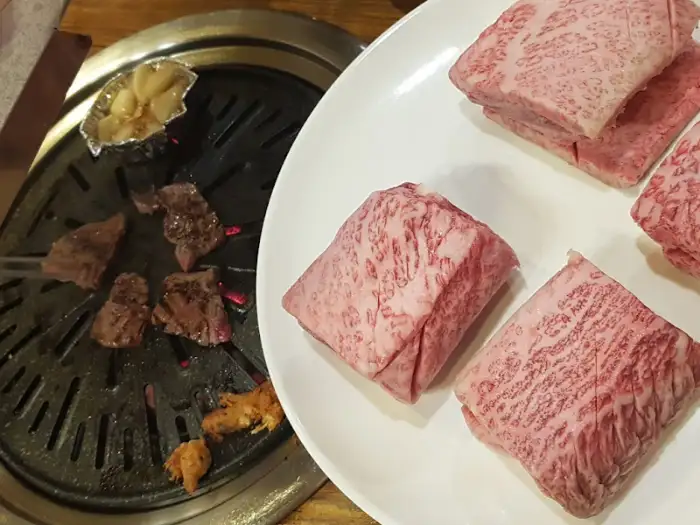 접시에 담긴 생 등심과 불판 위 익어가는 고기