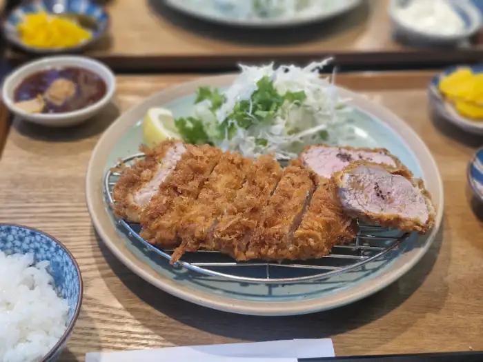 잘 썰린 돈까스가 접시에 담겨 있고 샐러드와 곁들여져 나옴