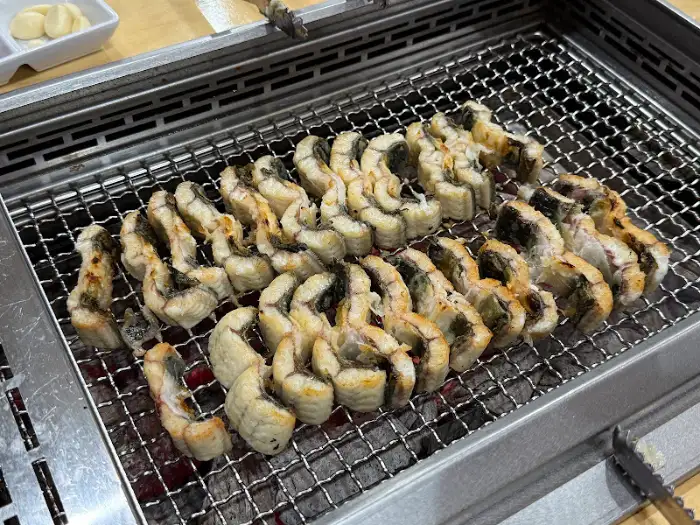 숯불 그릴 위에 빽빽하게 놓인 장어 조각들
