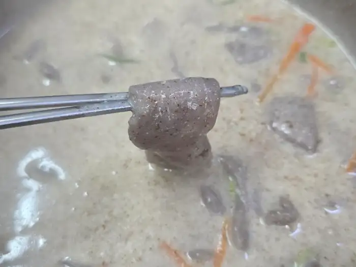 젓가락으로 집어 올린 두툼한 면발이 뽀얗고 부드러운 국물 안에 담겨 있다.