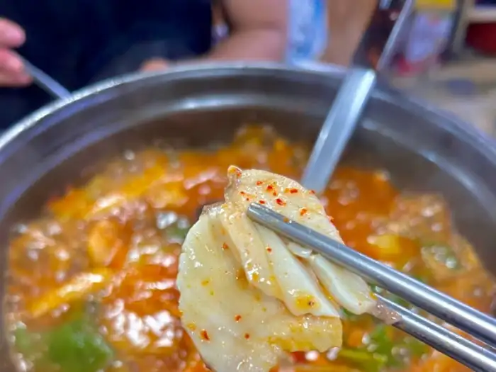 젓가락으로 매운탕 속의 생선살 한 점을 집은 모습.