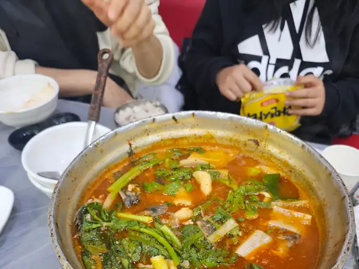 식탁에 놓인 매운탕 냄비와 주변의 식기들.