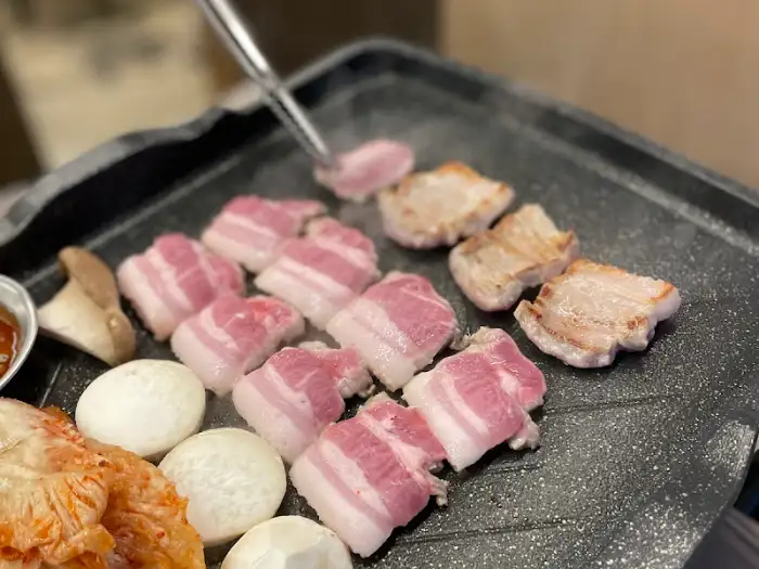 불판 위에서 익어가는 삼겹살과 곁들임