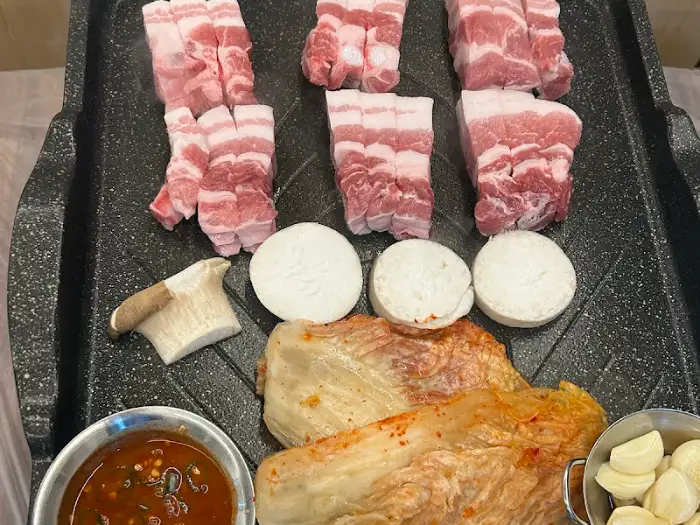불판 위에 가지런히 놓인 삼겹살 덩어리들