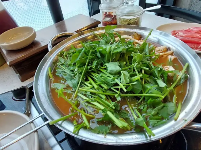 칼국수 냄비 위에 듬뿍 올라간 미나리와 채소