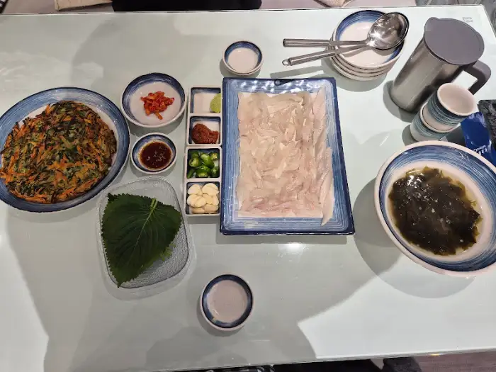 광어회, 파전, 곁들임 반찬, 밥그릇, 컵, 물병 등이 정갈하게 차려진 상차림
