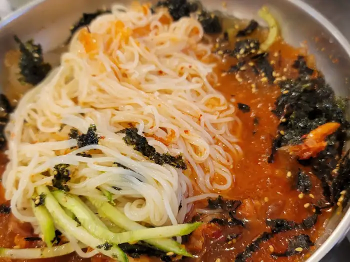 새콤달콤한 육수에 면과 김치, 해조류가 곁들여진 김치말이국수 사진