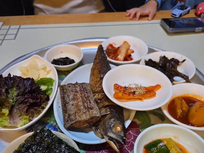 푸짐하게 차려진 생선정식백반 한 상. 여러 가지 반찬과 생선구이, 떡갈비 등이 보인다.