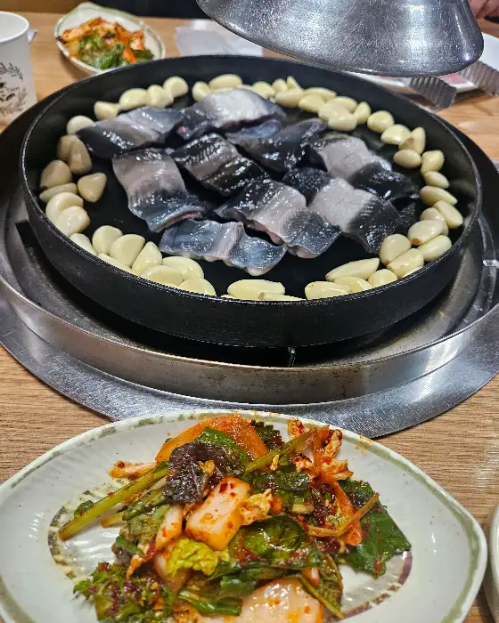 구워지고 있는 장어와 마늘, 그리고 김치 사진