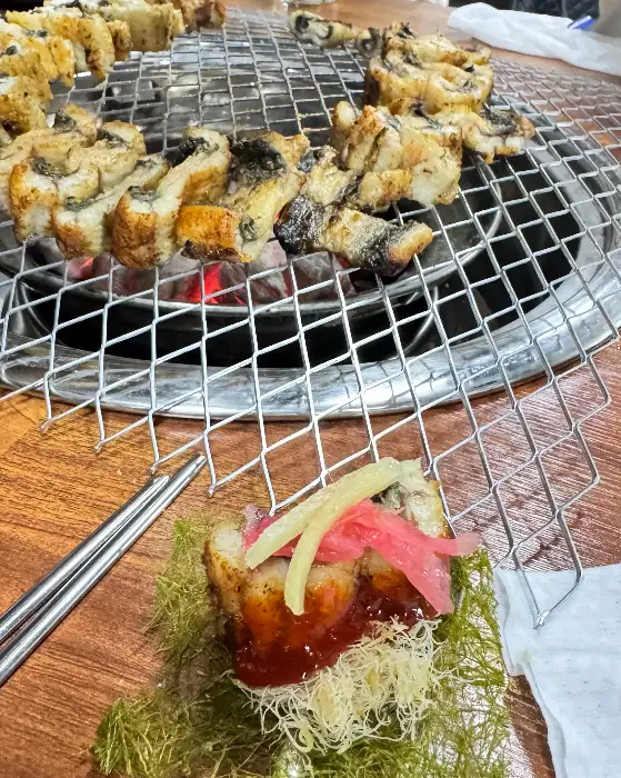 테이블 위 쌈으로 싸인 장어와 젓가락