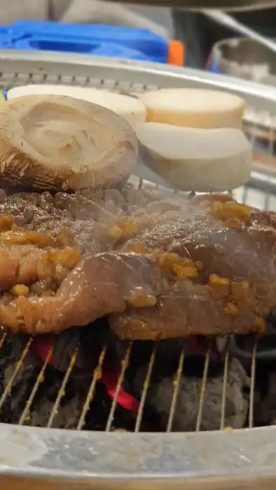 불판 위에서 구워지는 고기와 버섯