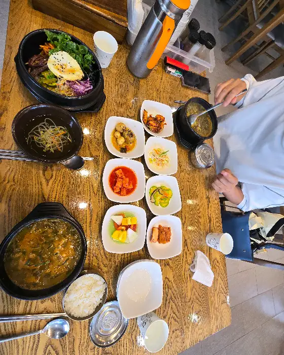 다양한 반찬과 추어탕, 돌솥밥이 놓인 식탁 모습.