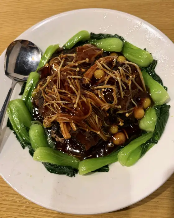 부드러운 동파육 조각들이 접시 중앙에 담겨 있고, 주변을 싱싱한 청경채가 둘러싸고 있습니다.