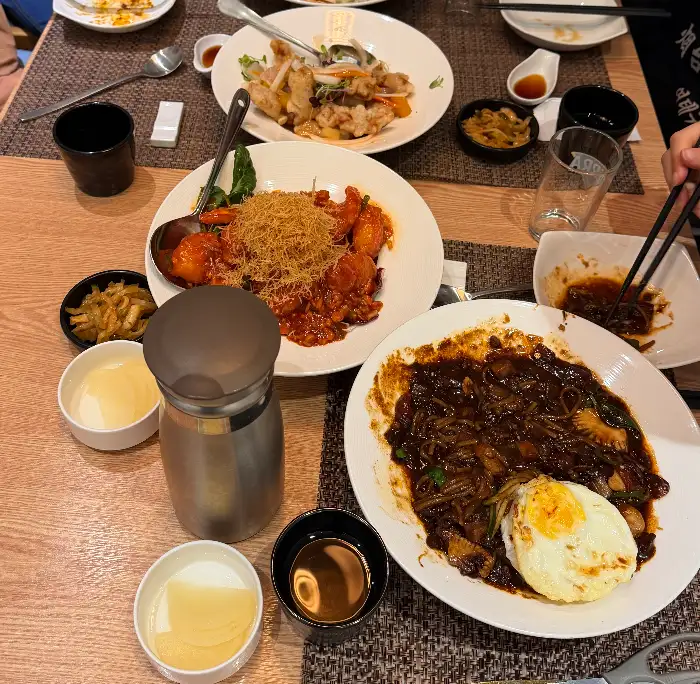 넓은 접시에 갓 튀겨진 탕수육 조각들이 가지런히 놓여 있고, 그 옆에는 새콤달콤한 탕수육 소스가 담긴 종지가 있습니다.