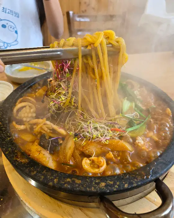 집게로 돌짜장 면발을 들어 올리는 모습