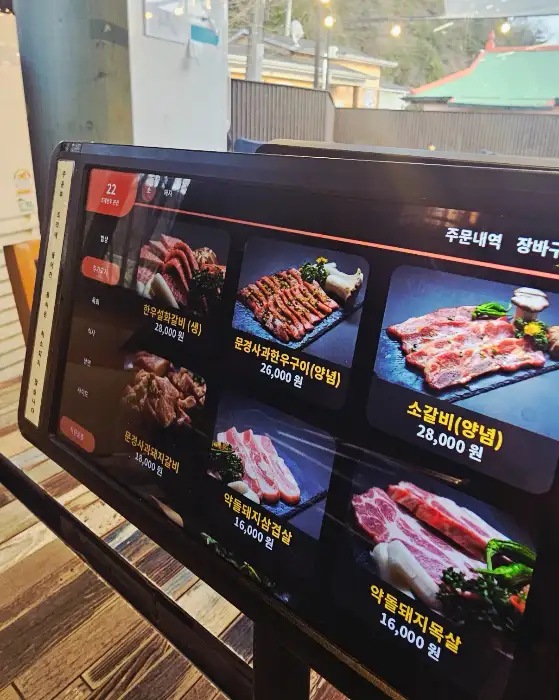 태블릿 메뉴판에 다양한 한우 및 돼지고기 메뉴 사진이 표시되어 있습니다.